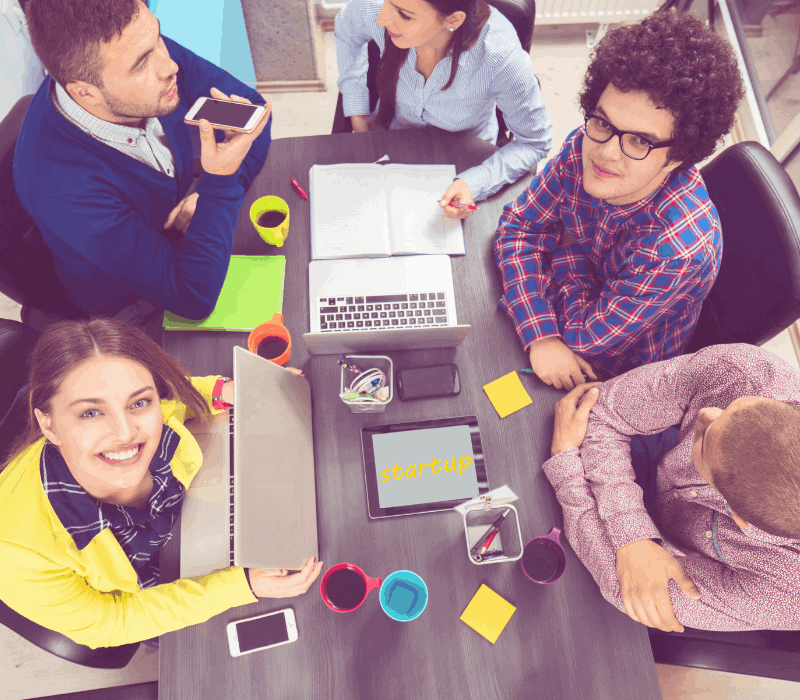 Invest in talent for successful tech ventures. Young talent around table with laptops.